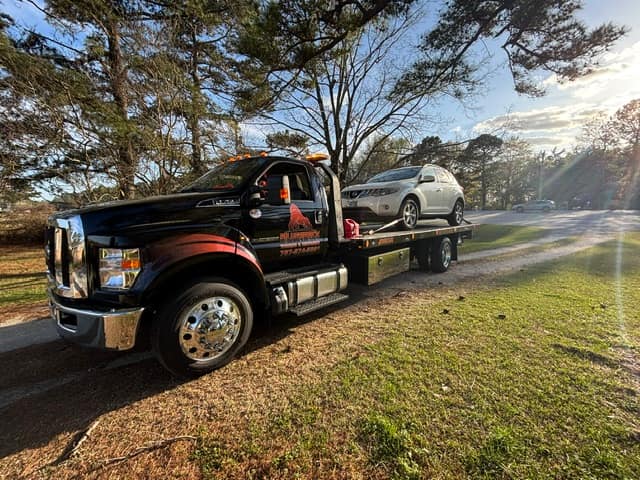 Silverback F-750 rollback with an SUV on the deck, parked on a grass shoulder