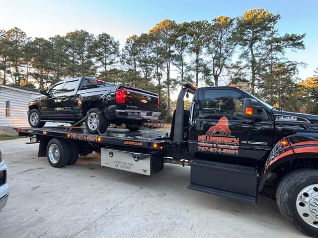 Black pickup loaded on the Silverback flatbed under tall pines