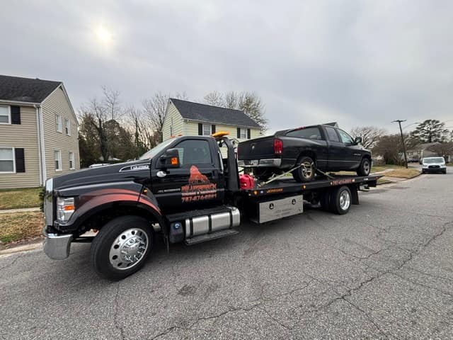 Black pickup towed down a residential street on the Silverback flatbed