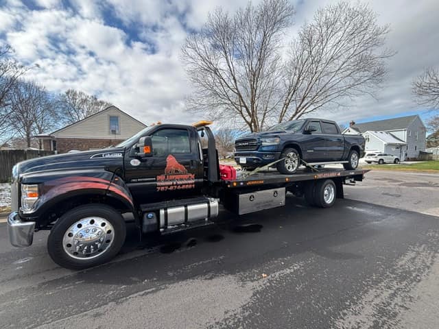Black Ram pickup towed through a neighborhood on the Silverback rollback
