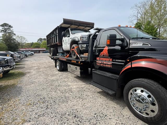 Silverback F-750 rollback hauling a white dump truck on the flatbed