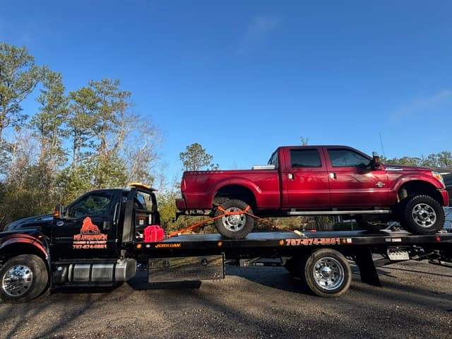 Red Ford pickup loaded on the Silverback flatbed tow truck
