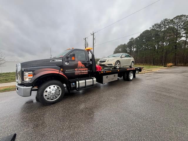 Sedan towed on a rainy rural road by the Silverback rollback