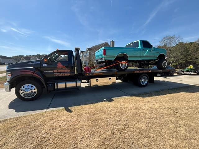 Teal pickup strapped down on the Silverback flatbed tow truck