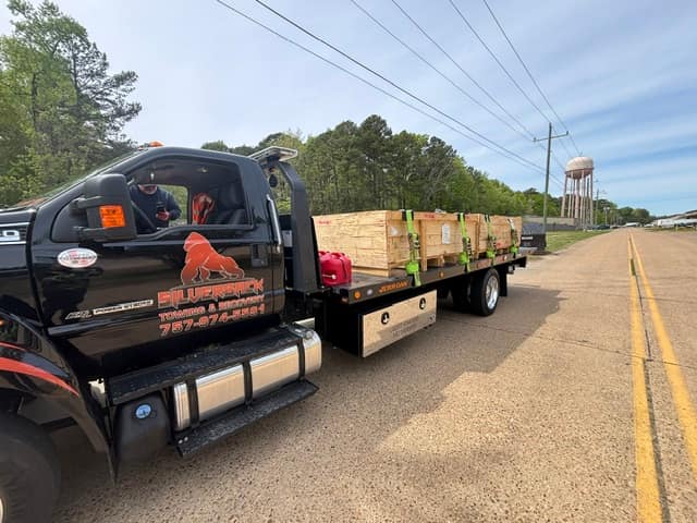Silverback rollback carrying a strapped lumber and material load down a two-lane road